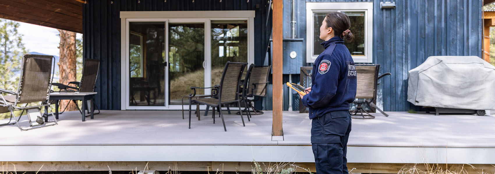 FireSmart BC home assessment being performed by woman in a blue uniform with tablet