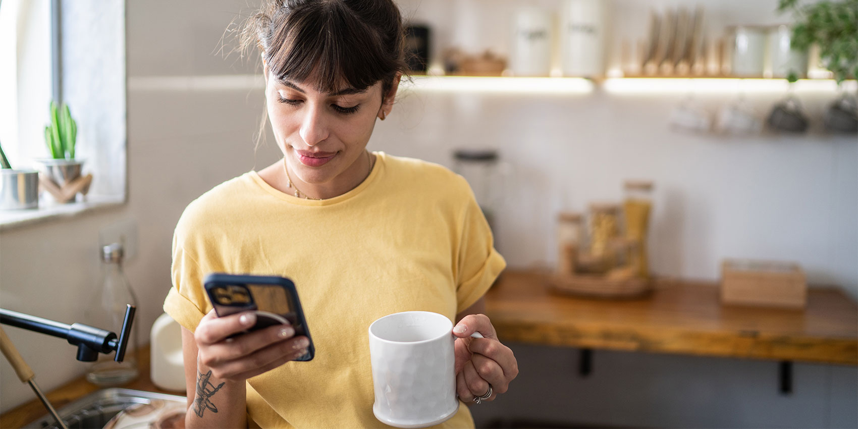 Woman drinking coffee and using mobile in the cafe