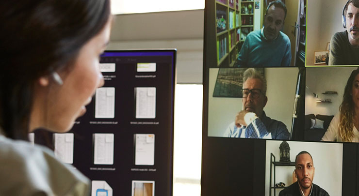 Woman faces computer screen filled with faces on a virtual meeting.