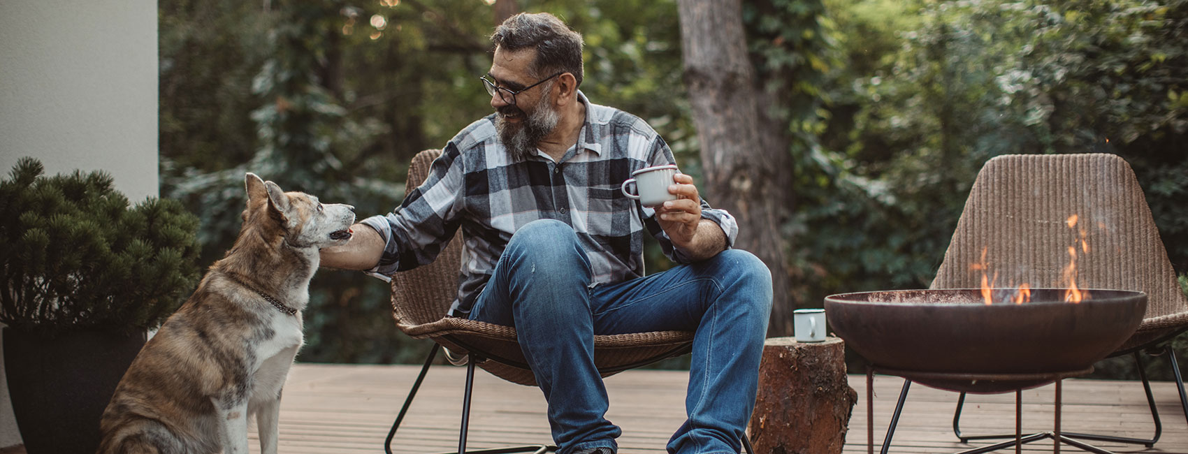 Men is resting and enjoying his evening tea on a porch with his dog