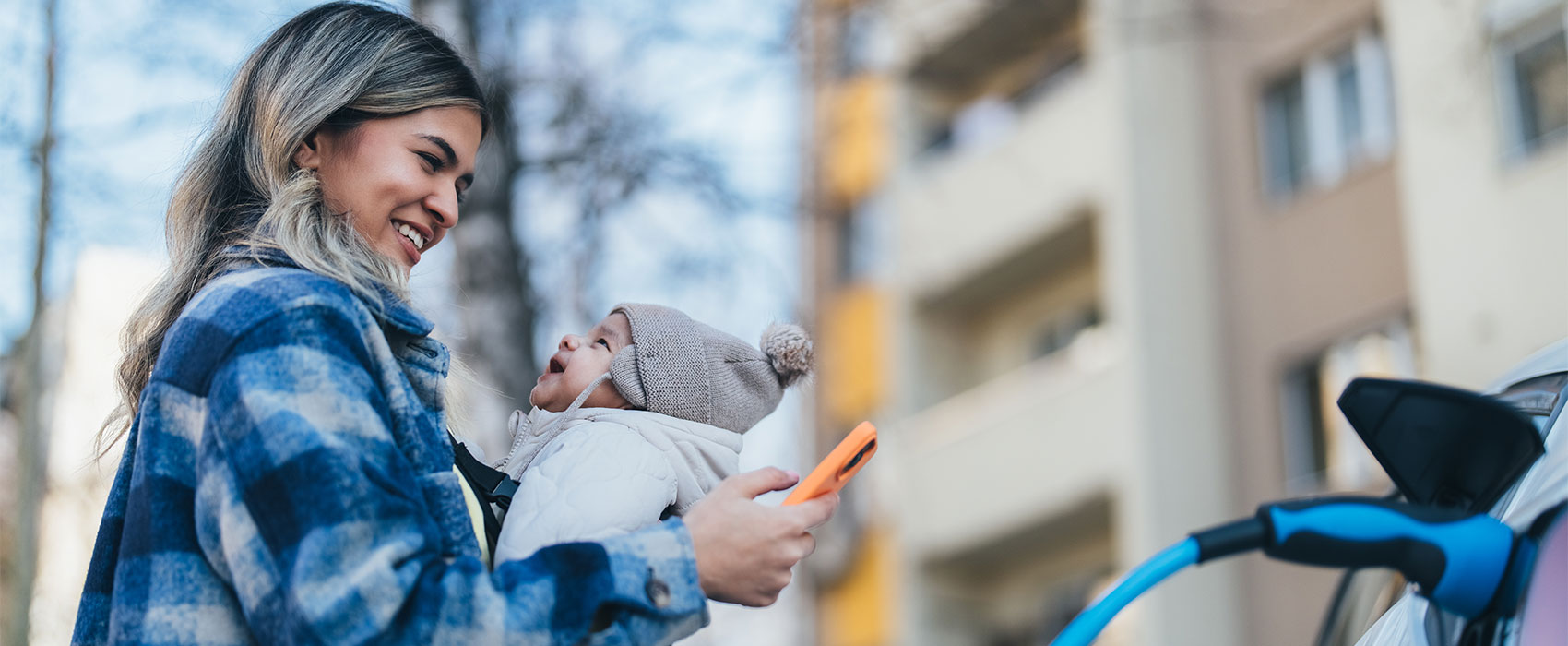 Woman with a baby charging EV car