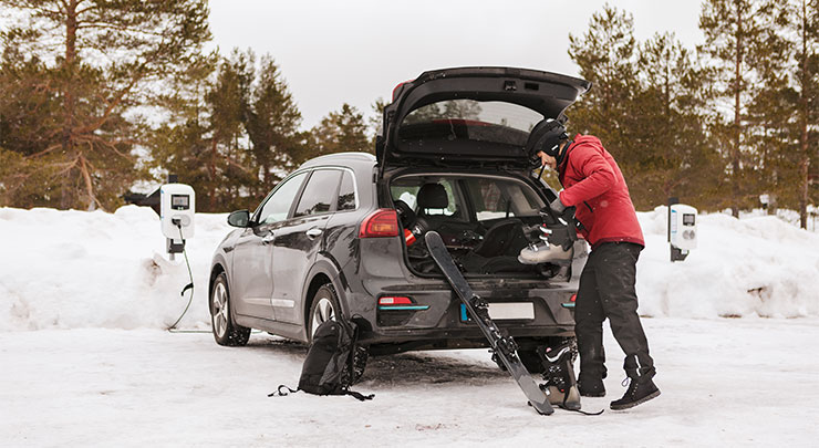 A ski-equipped man charging his EV car