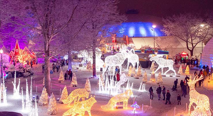 People walking amongst large light up sculptures in the snow at PNE Winter Fair