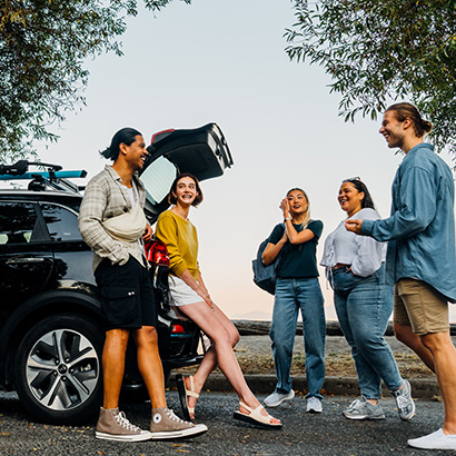 Group chatting near open trunk of an Evo