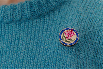 BCAA Fireweed Pin on a blue knitted sweater